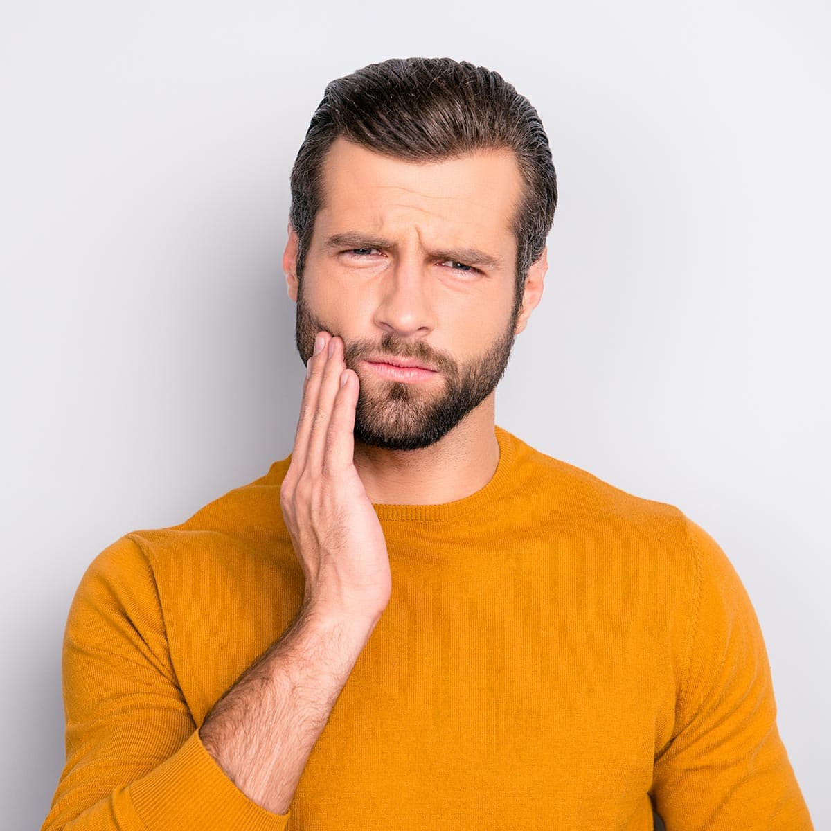 Man holding cheek in pain before tooth extraction
