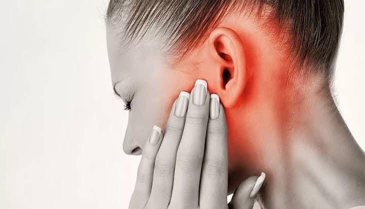 Woman holding her jaw near her ear, with red highlighting illustrating TMJ pain.